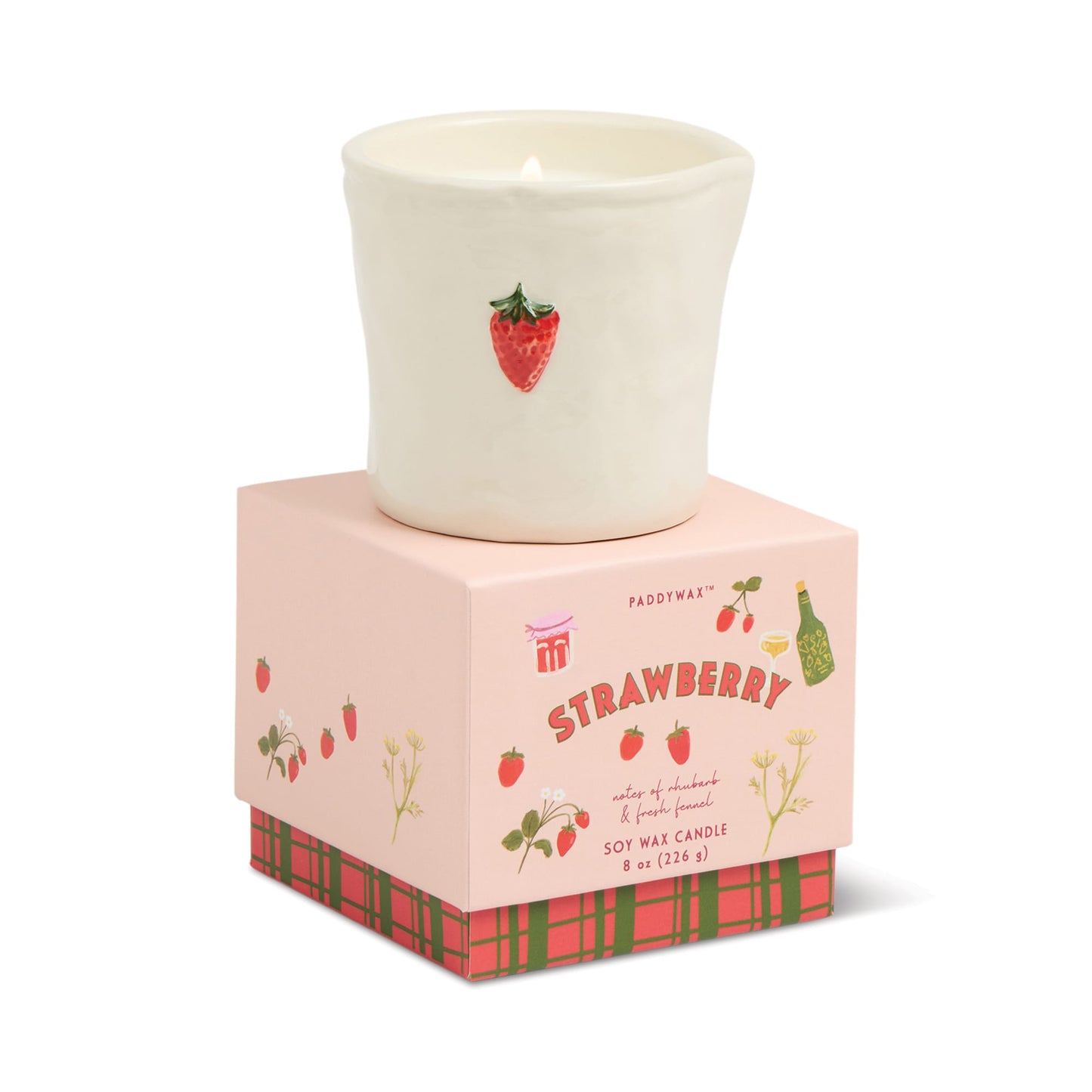 A lit white ceramic candle holder with a strawberry design sits on a pink "Strawberry" box featuring illustrations. The box notes it's the Strawberry - Bistro 8 oz Candle, an 8oz soy wax candle by Paddywax.