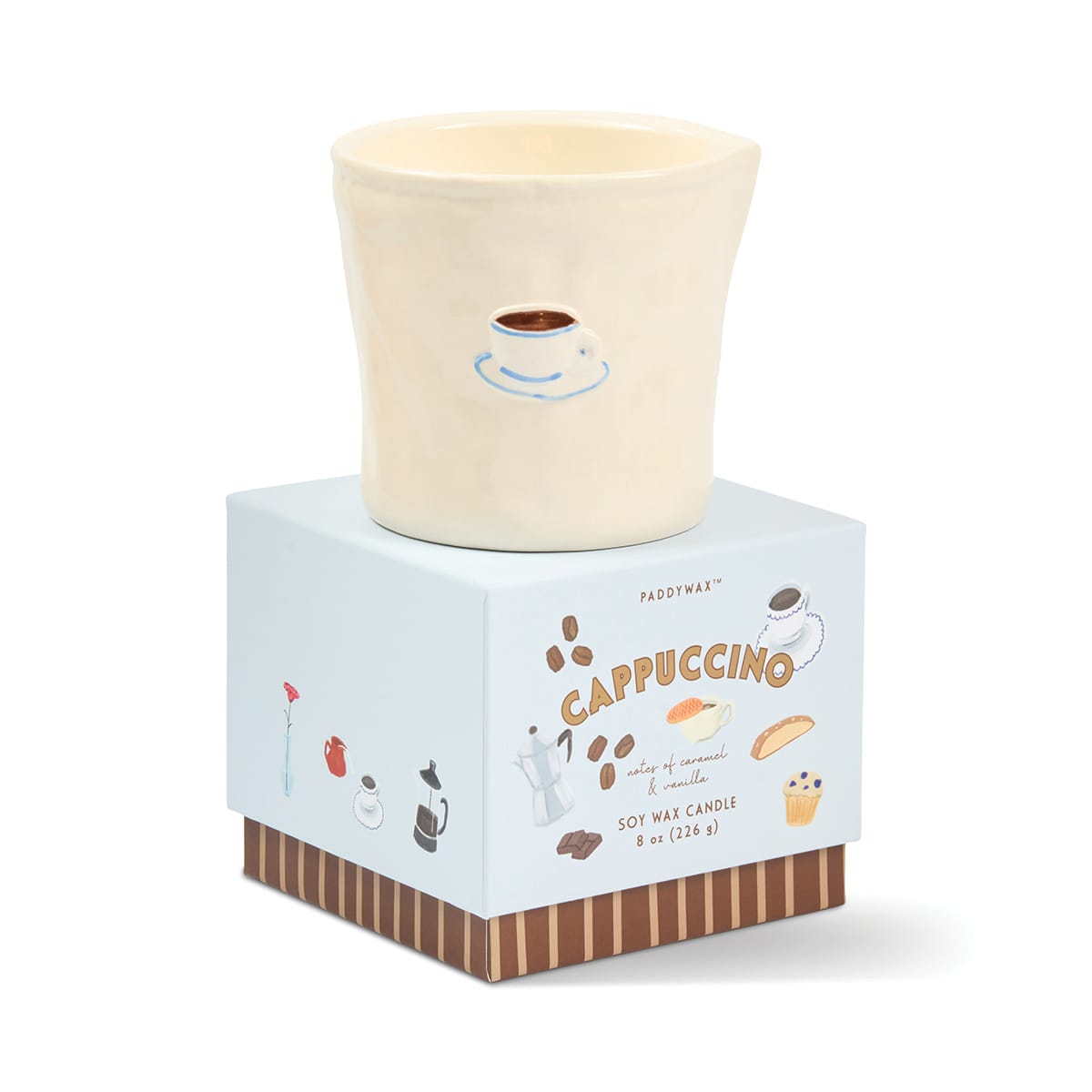 A cream-colored Cappuccino - Bistro 8 oz Candle, infused with a rich coffee aroma, is presented in a charming ceramic bistro cup and sits atop a box adorned with illustrations of coffee and pastries. The reusable ceramic vessel makes it both an eco-friendly choice and a delightful decor piece.