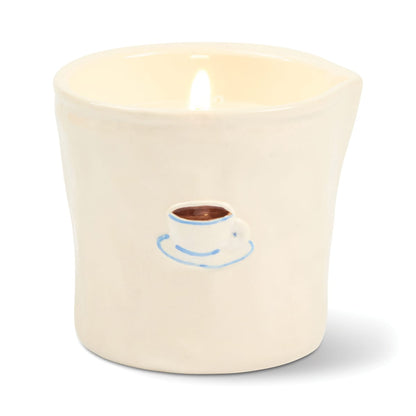 Light the Cappuccino - Bistro 8 oz Candle, presented in a cream-colored ceramic holder adorned with a hand-drawn coffee cup design. This coffee-scented candle fills your space with a cozy aroma and is housed in a reusable ceramic vessel for enduring charm.
