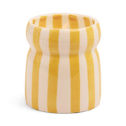 The Gold Coast - Cabana 6.5 oz Candle features a small ceramic vessel with vertical yellow and white stripes, a subtly indented middle, and evokes fresh coastal scents.