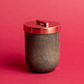 7 oz Green Blown Glass Candle; copper lid and white/copper hanging tag on red background
