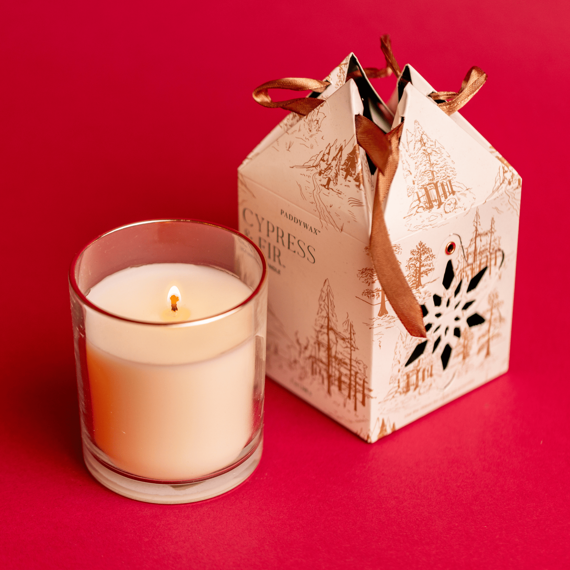 7 oz Glass Candle lit with Ornament Gift Box on red background from above
