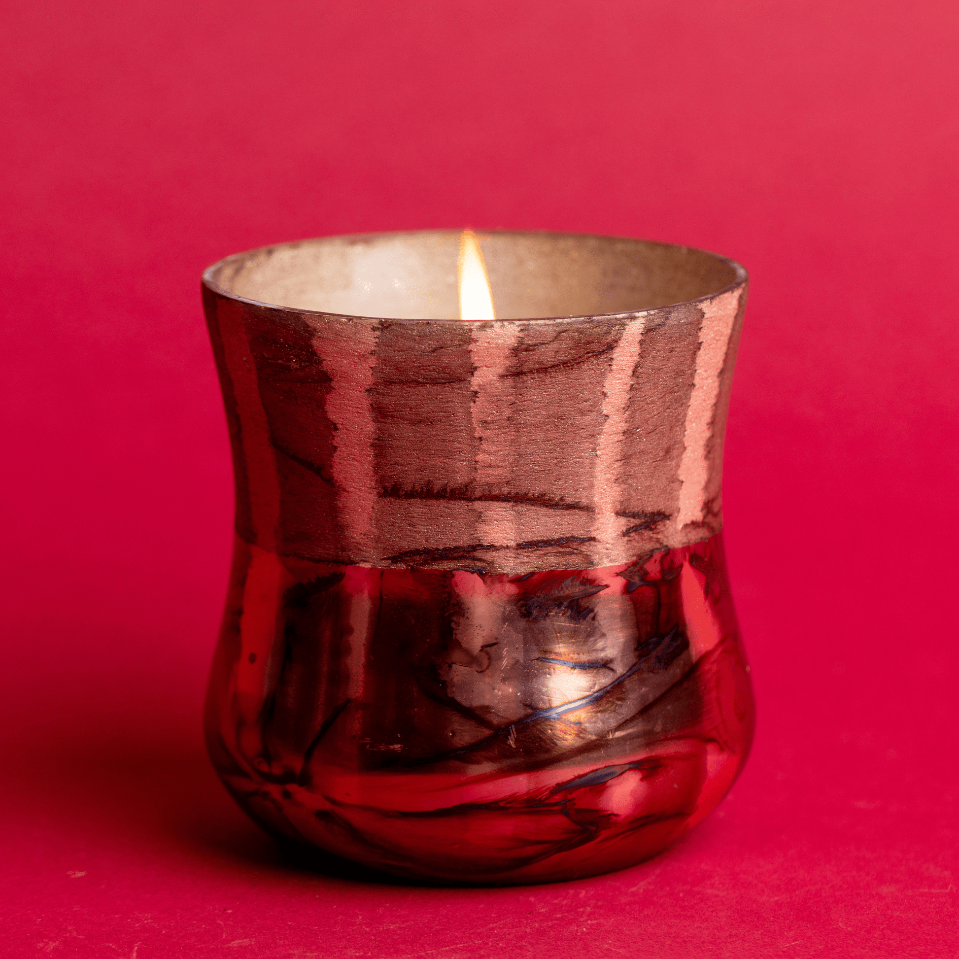 Lit Cypress & Fir - 9oz Frosted & Shiny Copper Metallic Glass candle on a red background.