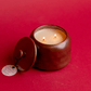 A lit, two wick Cypress & Fir - 11oz Bronzed Glazed Ceramic Jar candle on a red background