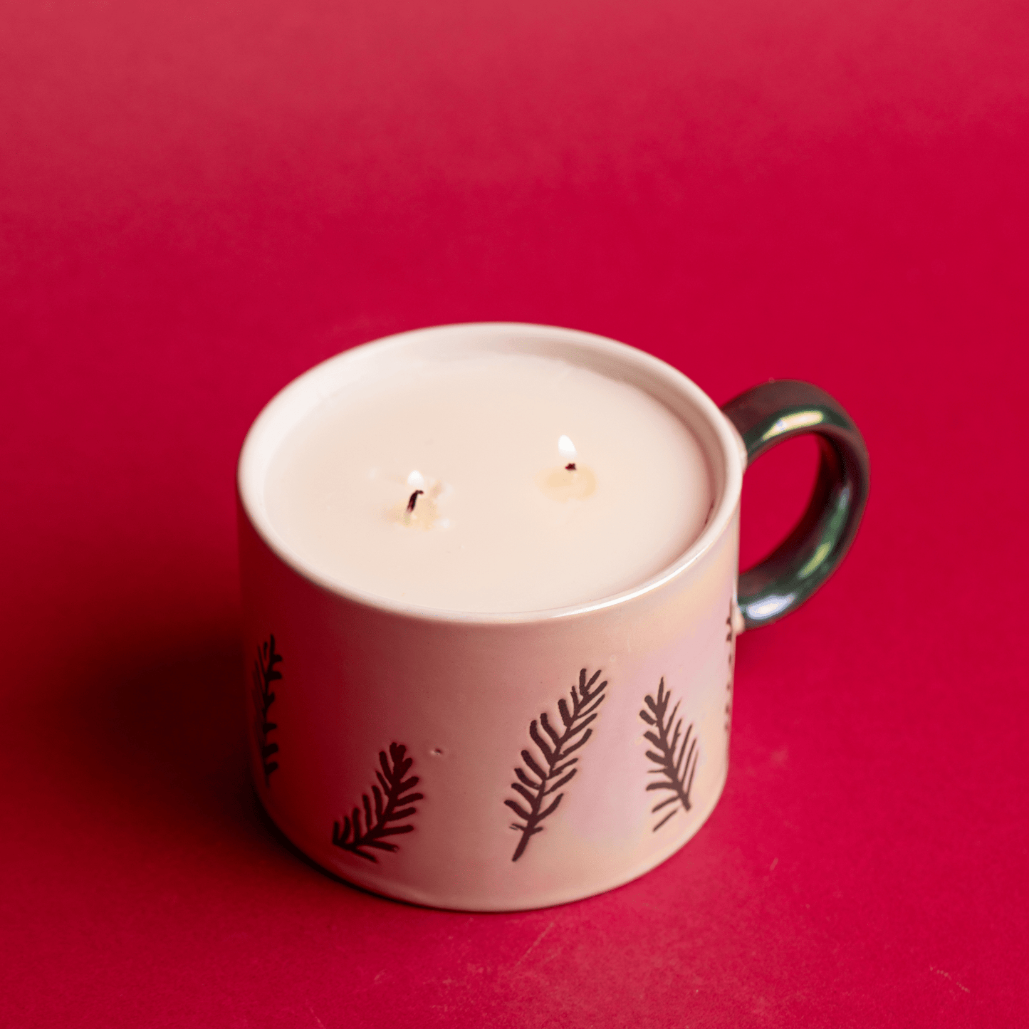 Top view of a lit Cypress & Fir - 8oz White Ceramic Mug candle on a red background