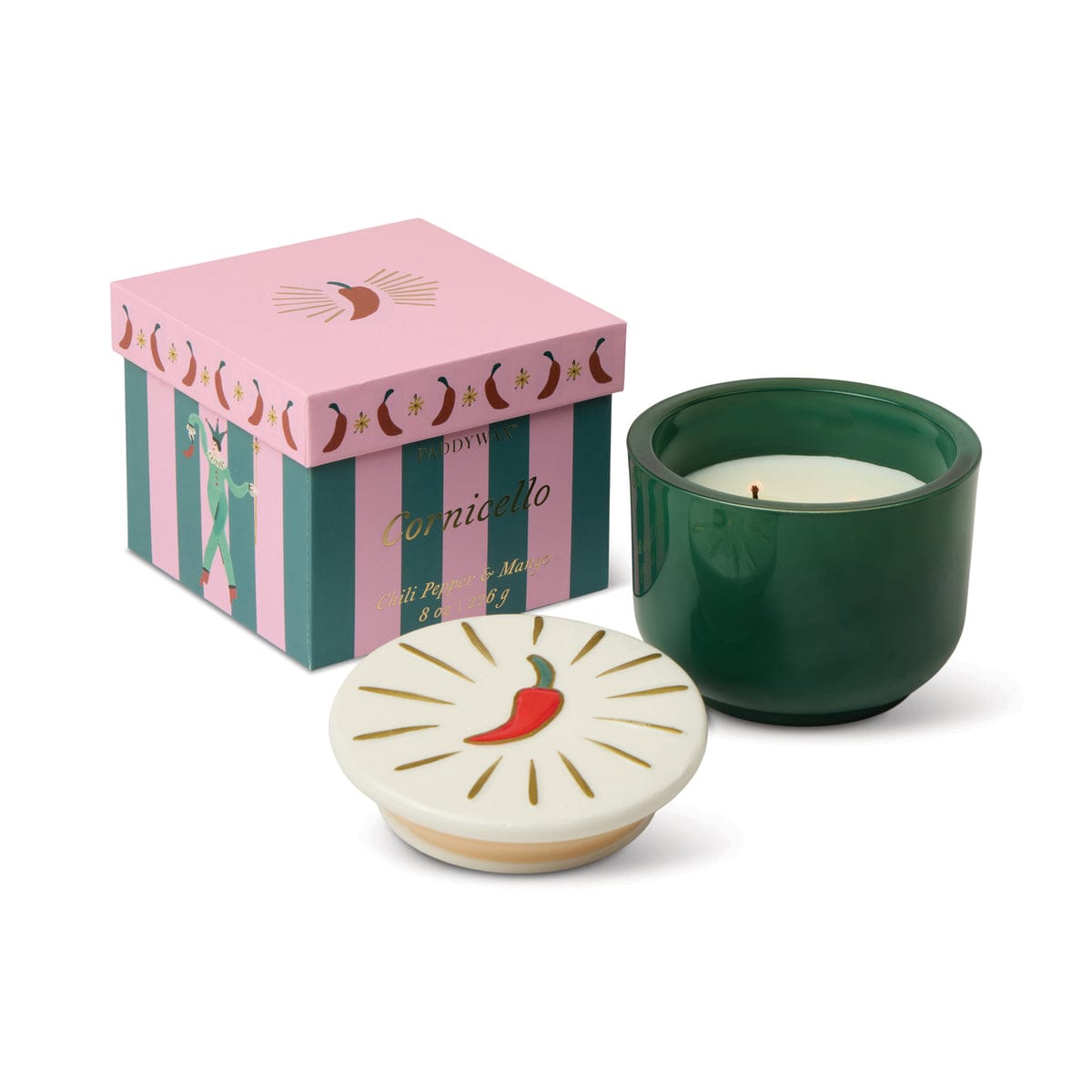 A Chili Pepper & Mango - Charmed 8oz Candle with a decorative ceramic lid featuring a red chili illustration sits beside a pink and green Cornicello-labeled box.