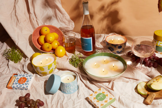 Terrace candle collection on an outdoor table with a table cloth with fruit and wine