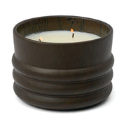 The Tobacco & Patchouli - Grain 12 oz Candle features a brown ribbed ceramic container with a lit white three-wick candle, filling the air with a rich tobacco patchouli scent.