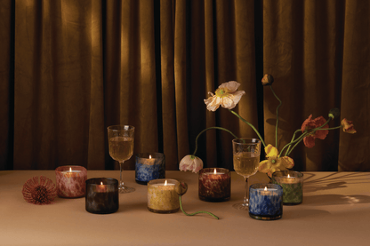 Candles from the Luxe collection with a brown curtain in the background. 