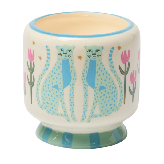 Hand-painted white ceramic cup featuring blue leopards, pink tulips, and gold stars, with a light blue rim and a base adorned with green and blue stripes. The interior is a creamy hue. This artisanal 8 oz Linen & Orris - A Dopo Candle provides an elegant home fragrance experience—perfect for display or gifting, especially when paired with your favorite Linen & Orris candle.
