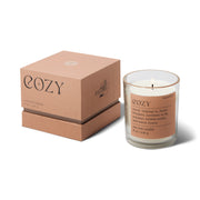 The Mood Collection 8oz - Cashmere + French Orris "Cozy" candle comes in a glass jar with a brown label, paired with a matching box. Its scent creates comfort and relaxation, making it perfect for a soothing, cozy atmosphere.