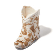 The Desert Peach - 6 oz Nashville Boot Candle features a ceramic boot shape with a white base and brown splatter pattern, inspired by Nashville cowboy boots—ideal for Tennessee-themed home decor. Photographed on a white background.