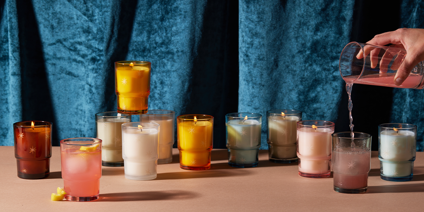 Noel glass candles showcasing the white soy wax candles and glass reusable vessels with hand pouring juice from pitcher into star glass container