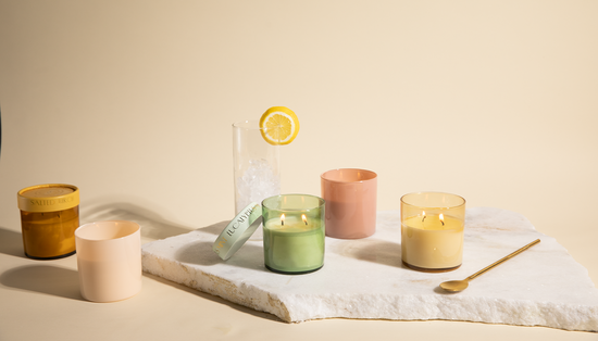 Optimist candle collection on a marble slab with a glass of ice