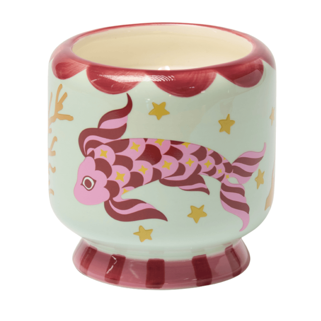 A hand-painted ceramic cup with red and pink koi fish, stars, and coral designs on a light green background, accented with red along the rim and base—perfect for holding your favorite Ocean Tide - A Dopo 8 oz Candle or sea salt candle.