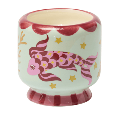 A hand-painted ceramic cup with red and pink koi fish, stars, and coral designs on a light green background, accented with red along the rim and base—perfect for holding your favorite Ocean Tide - A Dopo 8 oz Candle or sea salt candle.