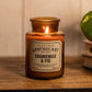 Chamomile & Fig Apothecary candle on a wooden shelf next to a plant