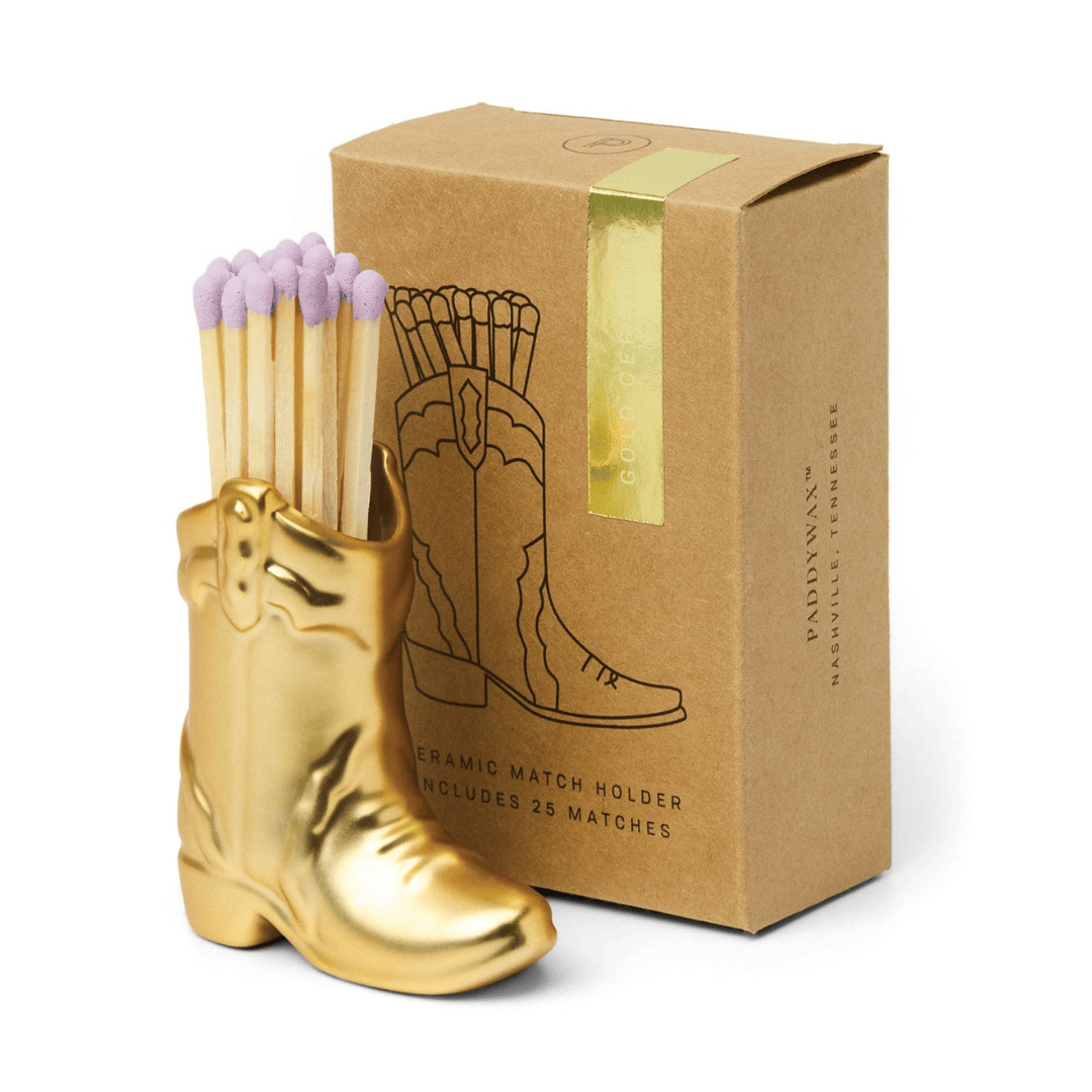 Gold boot-shaped match holder with matches and a matching box on a white background
