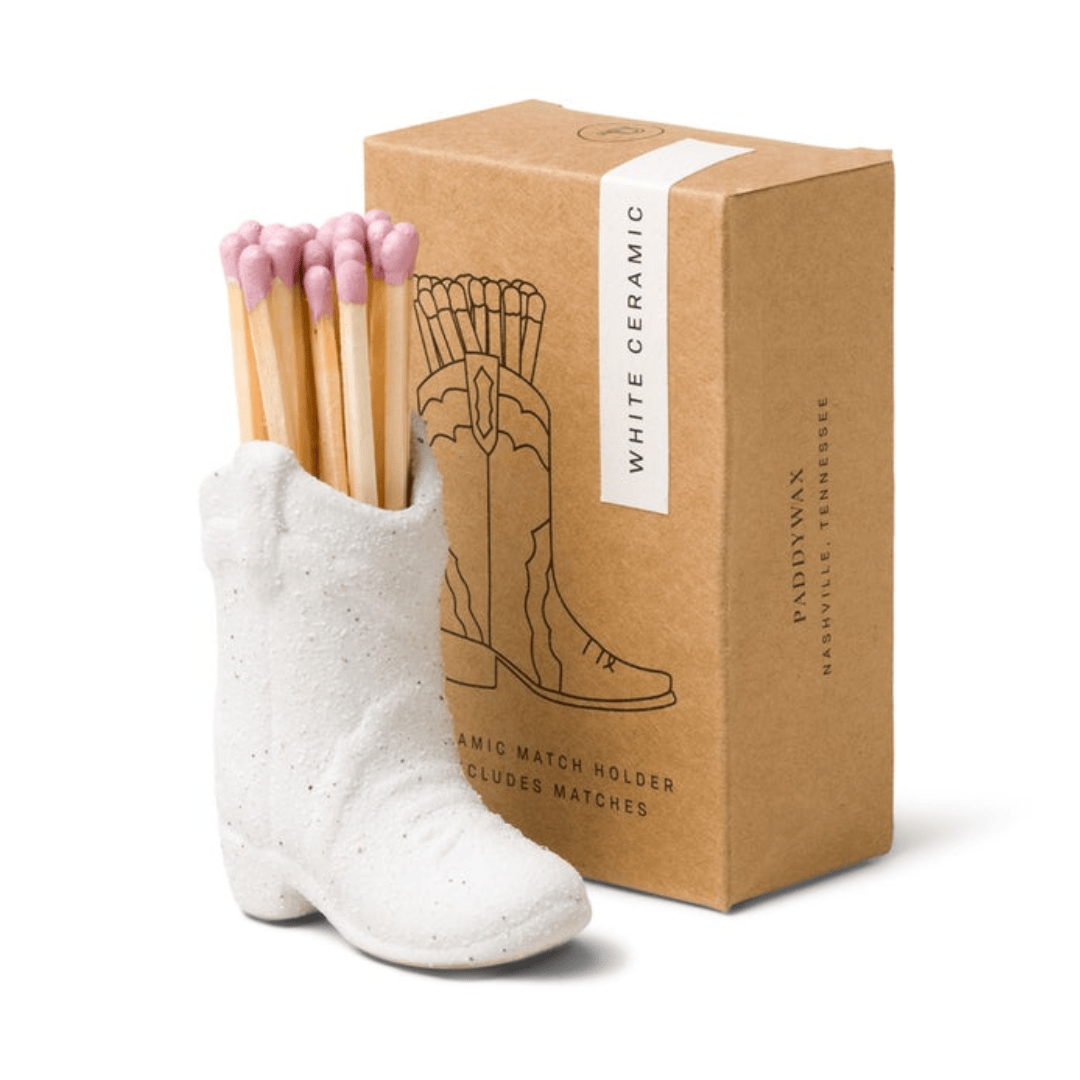 White ceramic boot match holder with matches and a brown packaging box on a white background