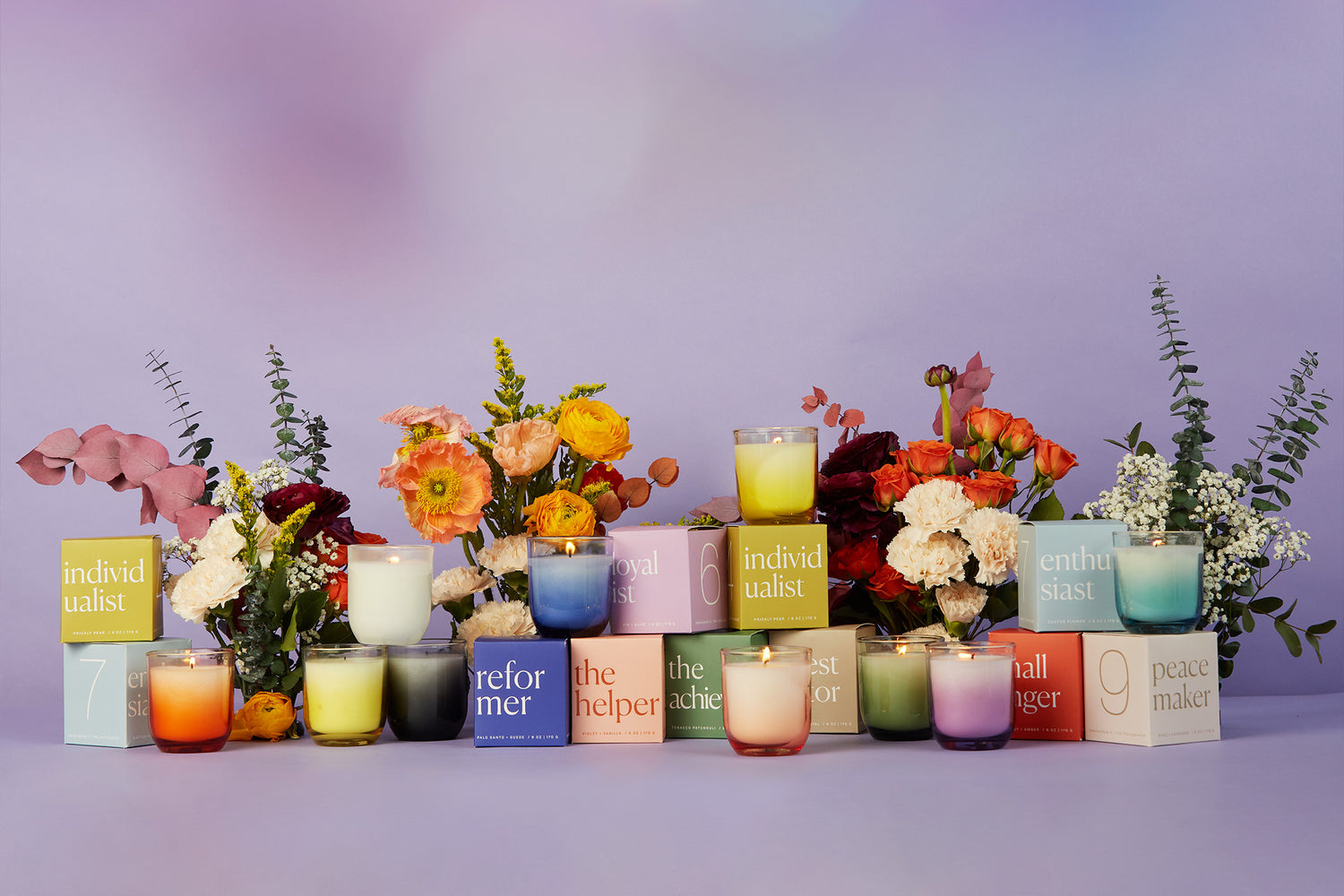 Enneagram candle collection with packaging and floral arrangements around the scented candles and candle packaging