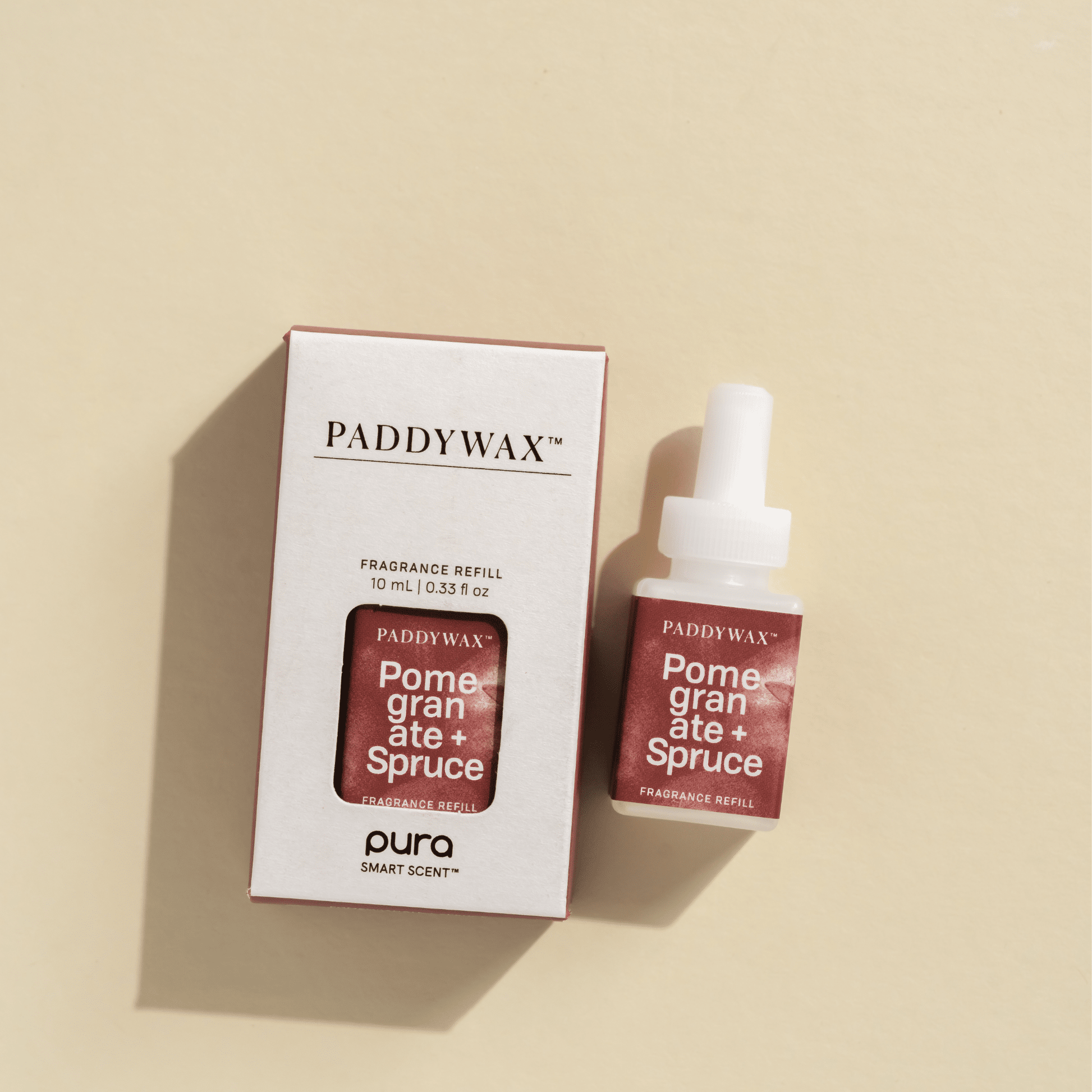 Paddywax Pomegranate and Spruce Pura fragrance refills laying on pale surface
