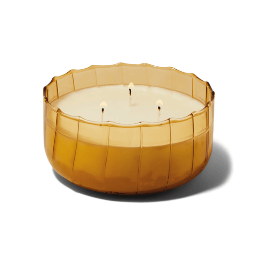 The Golden Ember - Ripple 12 oz Candle features a round ribbed amber glass vessel with creamy white wax and four wicks, making it ideal as vintage table decor.