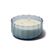 The Peppered Indigo - Ripple 12 oz Candle features three wicks in a round, translucent blue ribbed glass container, shown against a white background.