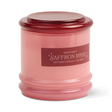 The Saffron Rose - Stack 7 oz Candle features a pink glass jar with matching lid, dark pink label with white text and small stars, and a reusable container that adds charm to this rose-scented soy wax candle.
