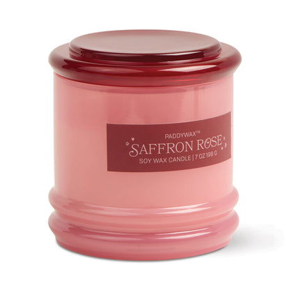 The Saffron Rose - Stack 7 oz Candle features a pink glass jar with matching lid, dark pink label with white text and small stars, and a reusable container that adds charm to this rose-scented soy wax candle.