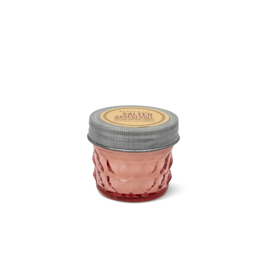 A small glass jar candle with a textured pink body, a silver metal lid, and a round beige label reading 'SALTED' and 'Bergamot Scented Candle'.