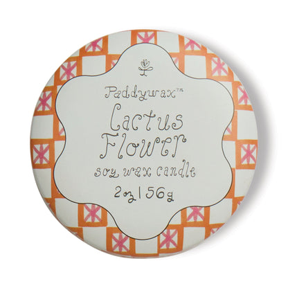 The Cactus Flower - Tulip 2 oz Tin Candle features a round tin with a white scalloped lid and vibrant orange and pink geometric designs, capturing the fragrance of desert blooms in soy wax.