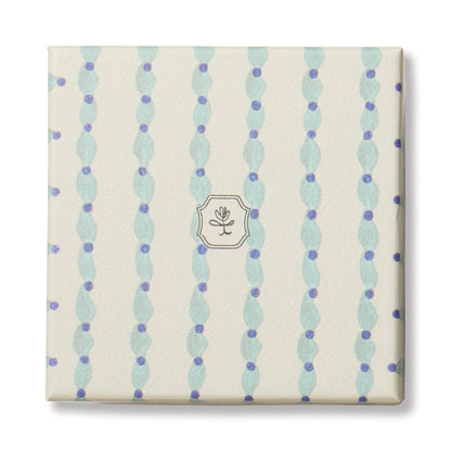 The Wisteria & Willow - Tulip 5.5 oz Candle comes in a square, cream box with wavy blue stripes, purple dots, and a central emblem showing a minimalist leaf inside a thin hexagonal border.