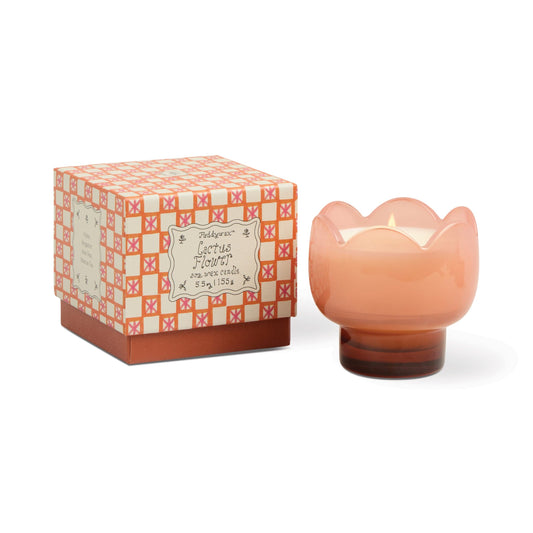 A pink, flower-shaped Cactus Flower - Tulip 5.5 oz Candle in a glass holder sits beside its matching decorative box adorned with an orange and pink geometric pattern—a delightful accent for your home decor.