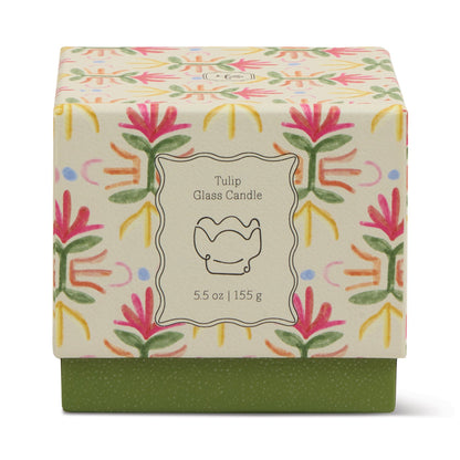The Bronzed Gardenia - Tulip 5.5 oz Candle comes in a decorative box with a pink, green, and yellow tulip pattern featuring a simple candle illustration—perfect for adding floral style to your home decor.