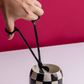 Human hand, black wick trimmer and candle on white table with red background