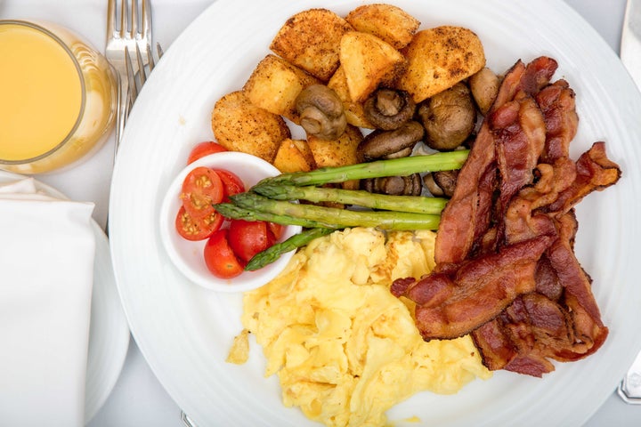 Bacon with eggs, potatoes, and vegetables on plate