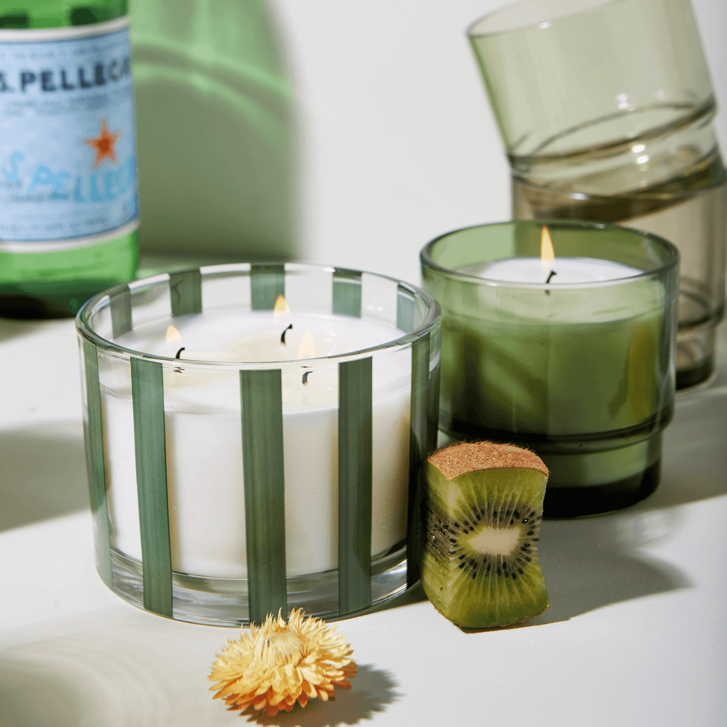 clear glass vessel green stripes, white wax, and three wicks; a part of the Al Fresco collection; comes with woven rattan lid; pictured next to another green candle.