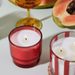7 oz Al Fresco candle with a bright red-tinted glass vessel pictured next to the matching 12 oz striped Al Fresco candle