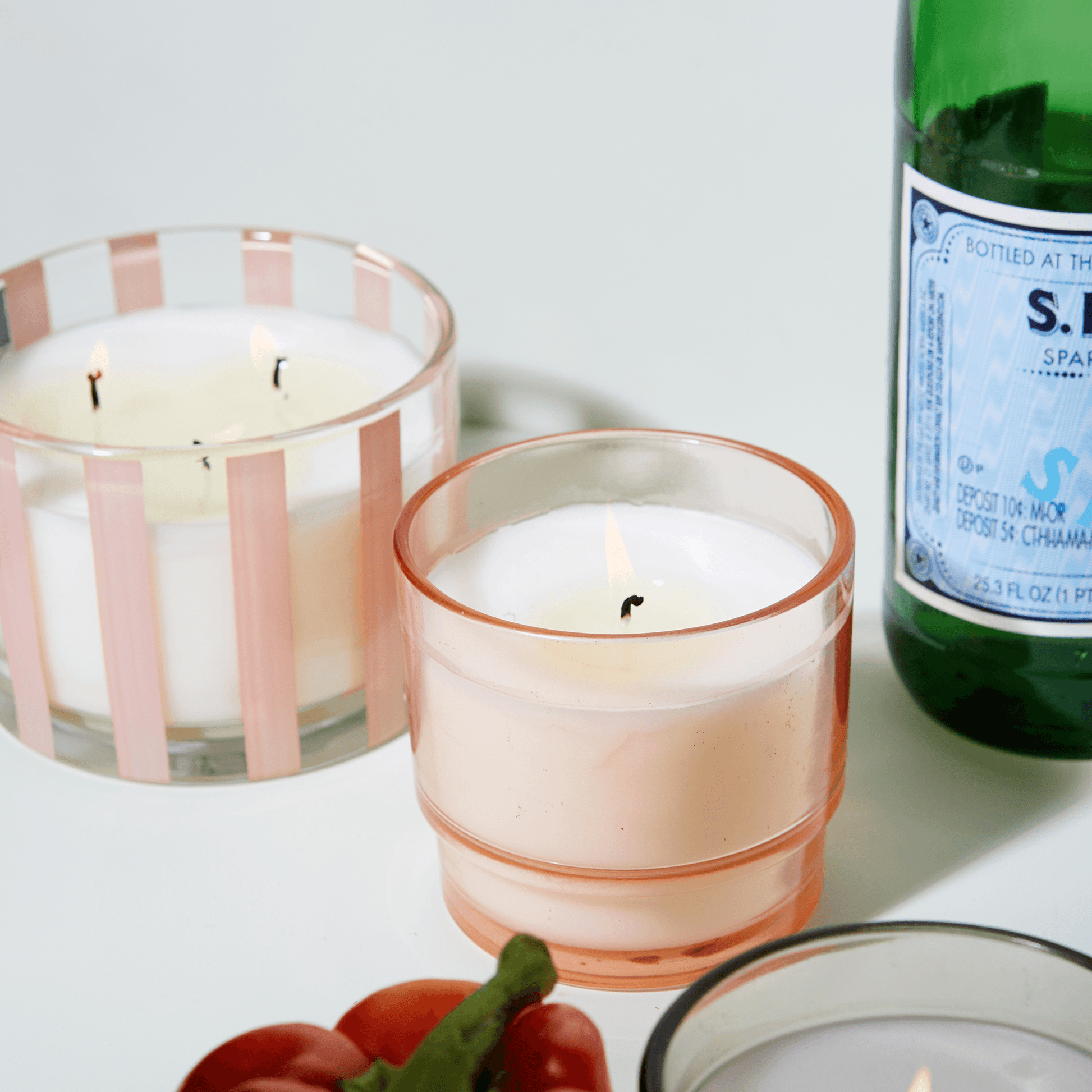 7 oz Al Fresco candle with a light pink vessel pictured next to the larger 12oz Al Fresco candle of the same color.
