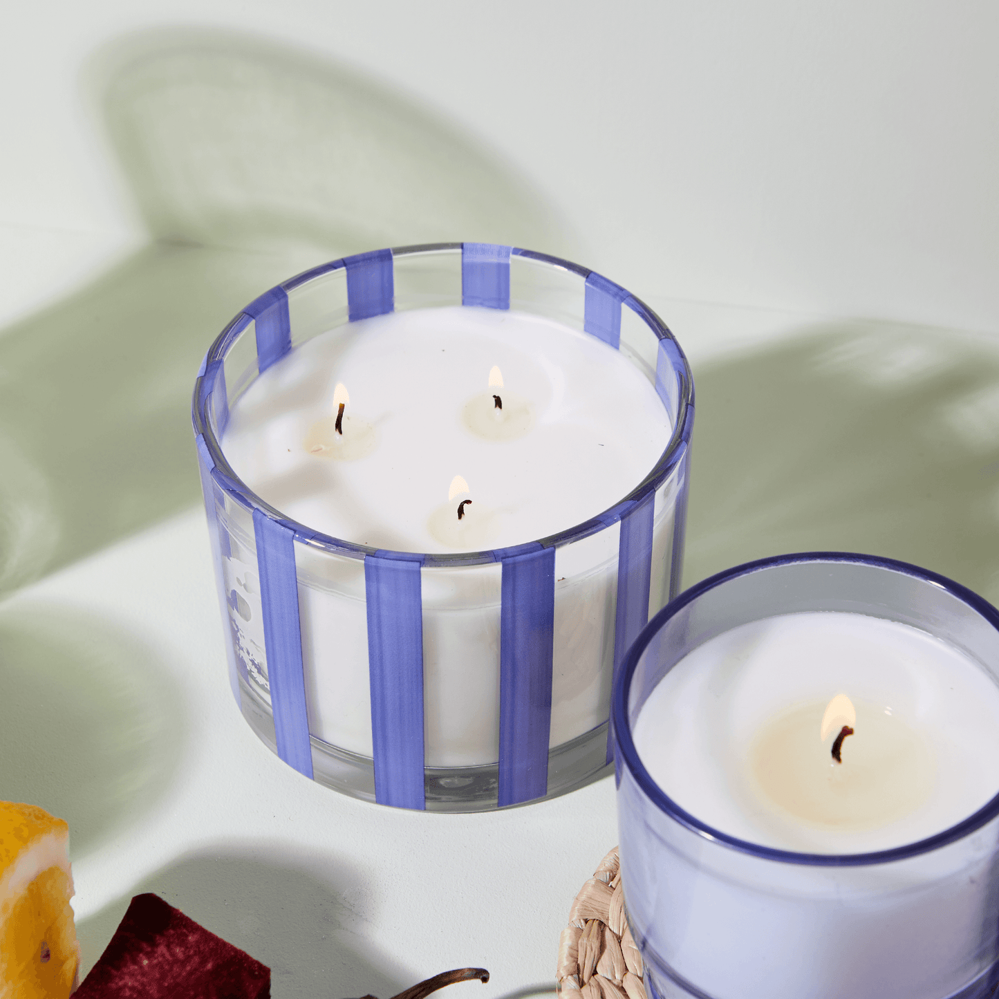Blue/purple Al Fresco candle pictured lit next to a smaller candle of the same color but solidly colored.