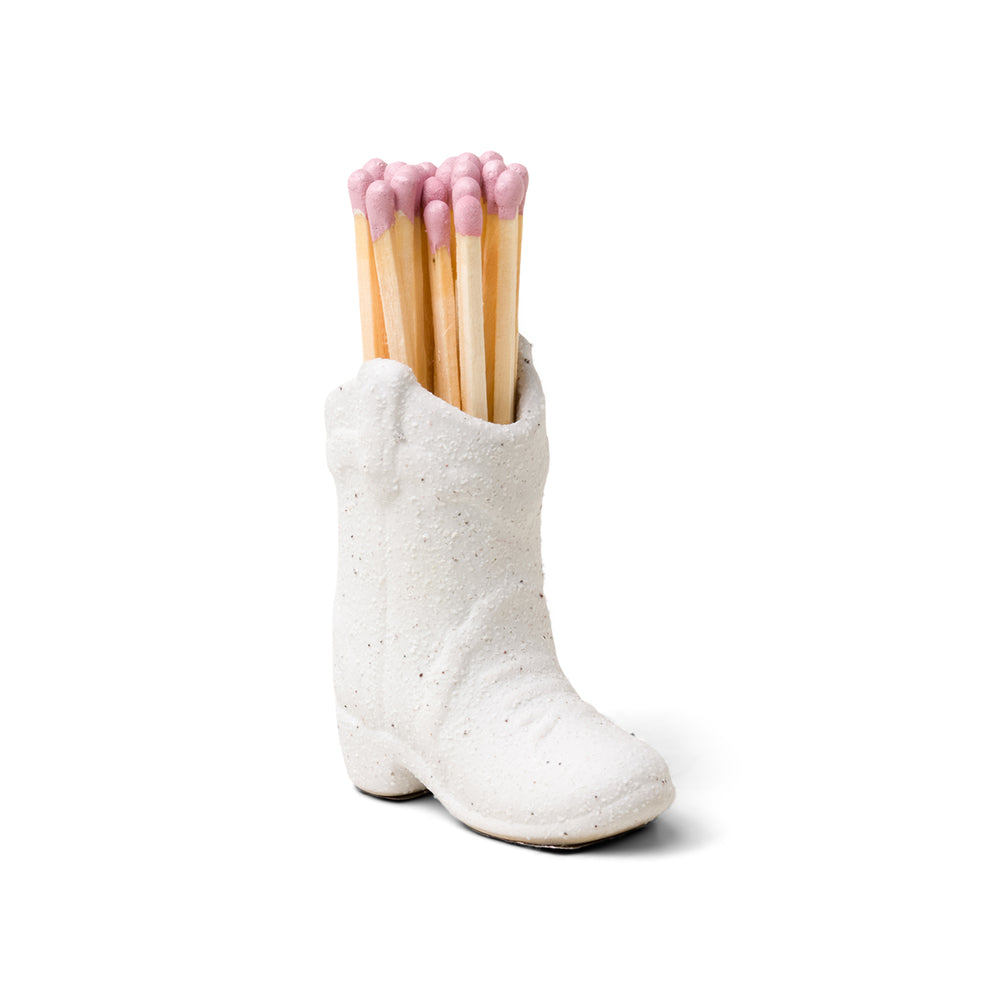 small white ceramic cowboy boot pictured holding pink-tipped matches 