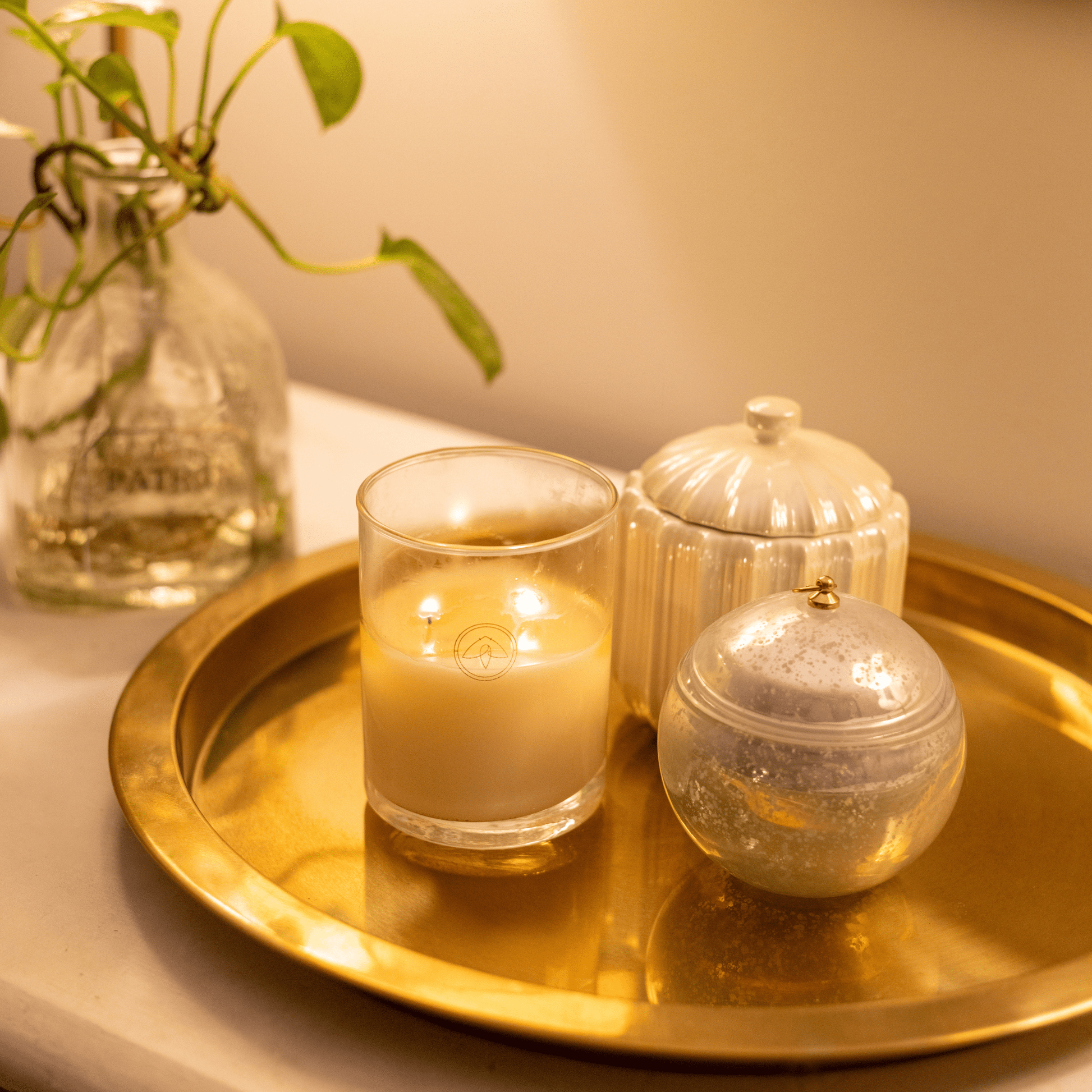 10oz Clarity two wick candle on gold metal tray with home decor and a planter in the background