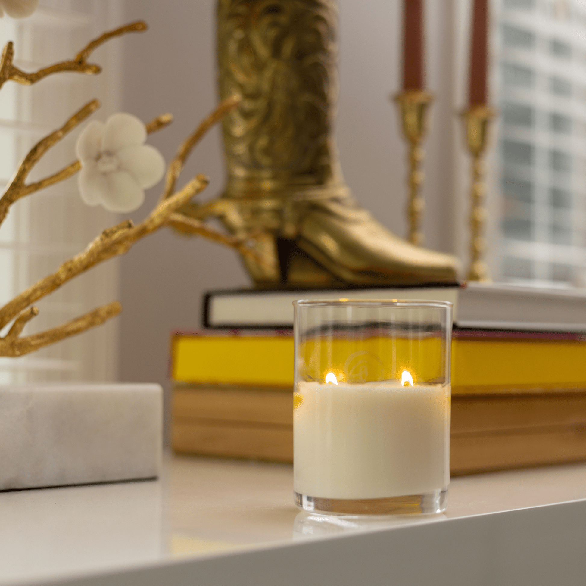 Clarity 10oz candle on table with books and home decor in background