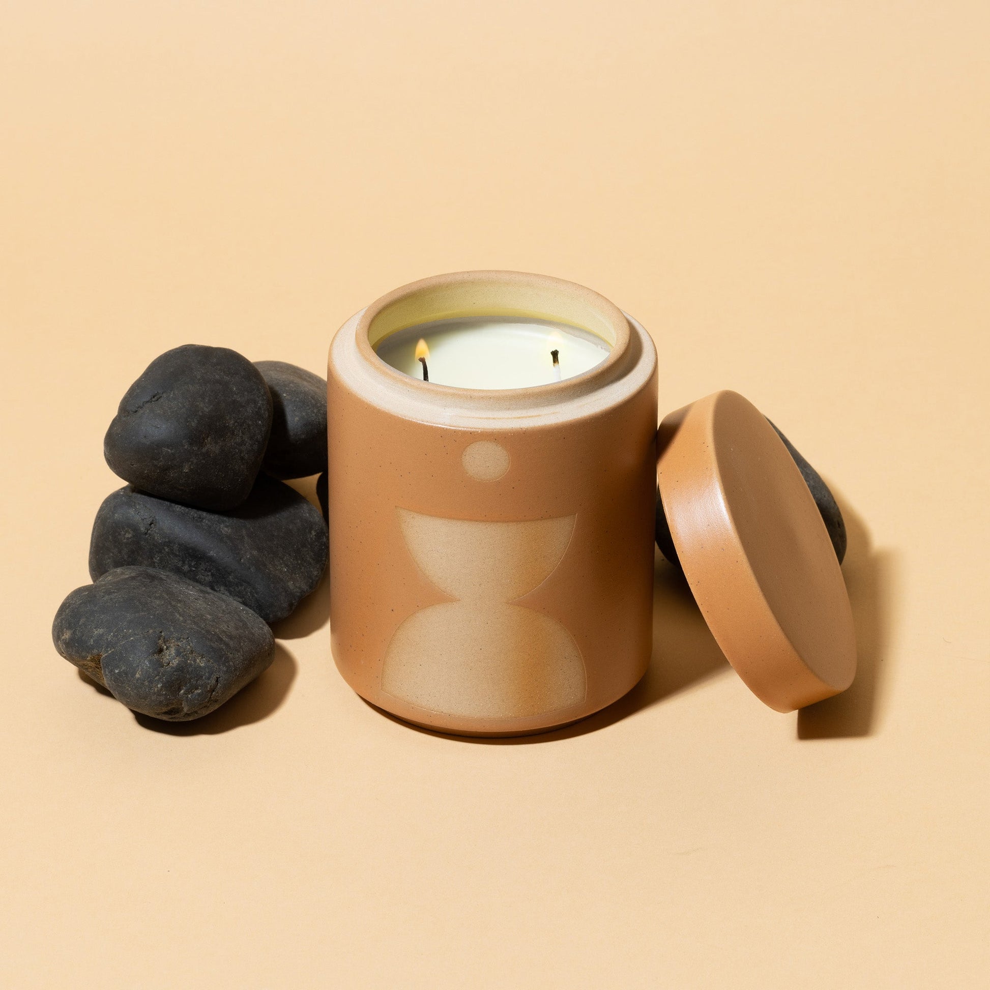 12 oz copper-colored cylindrical ceramic vessel with ceramic lid; white wax and two cotton wicks; reflected beige mirrored semi-circle design on the side