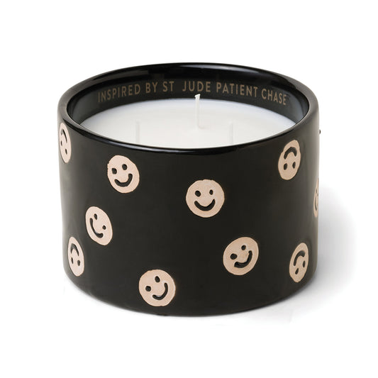 Black ceramic candle with smiley faces and white soy wax center with three wicks. Debossed name on back side of the label with text "Inspired by St. Jude patient Chase". Scented candle on white background