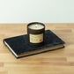 Library Edgar Allan Poe soy wax candle with single wick burning on top of book on hardwood surface