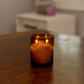 10oz Glow two wick candle on dark wood table top with soft focused background