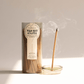 Green glass cylinder with white label holding 100 incense sticks for flameless fragrance; pictured next to burning incense stick