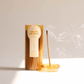 Yellow glass cylinder with white label holding 100 incense sticks for flameless fragrance; pictured next to burning incense stick