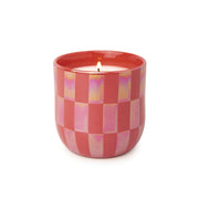 A lit Cactus Flower - Lustre Candle 10 oz glows in a pink, checkered ceramic holder against a white background.